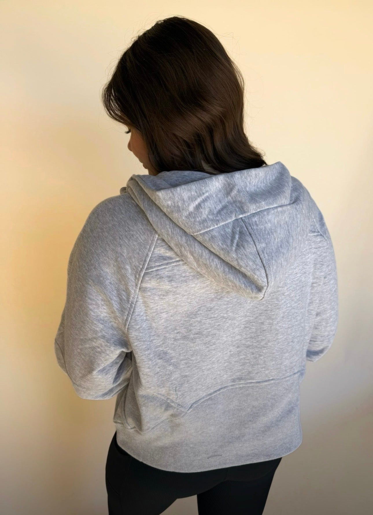 Person wearing a gray hoodie from behind on a plain background