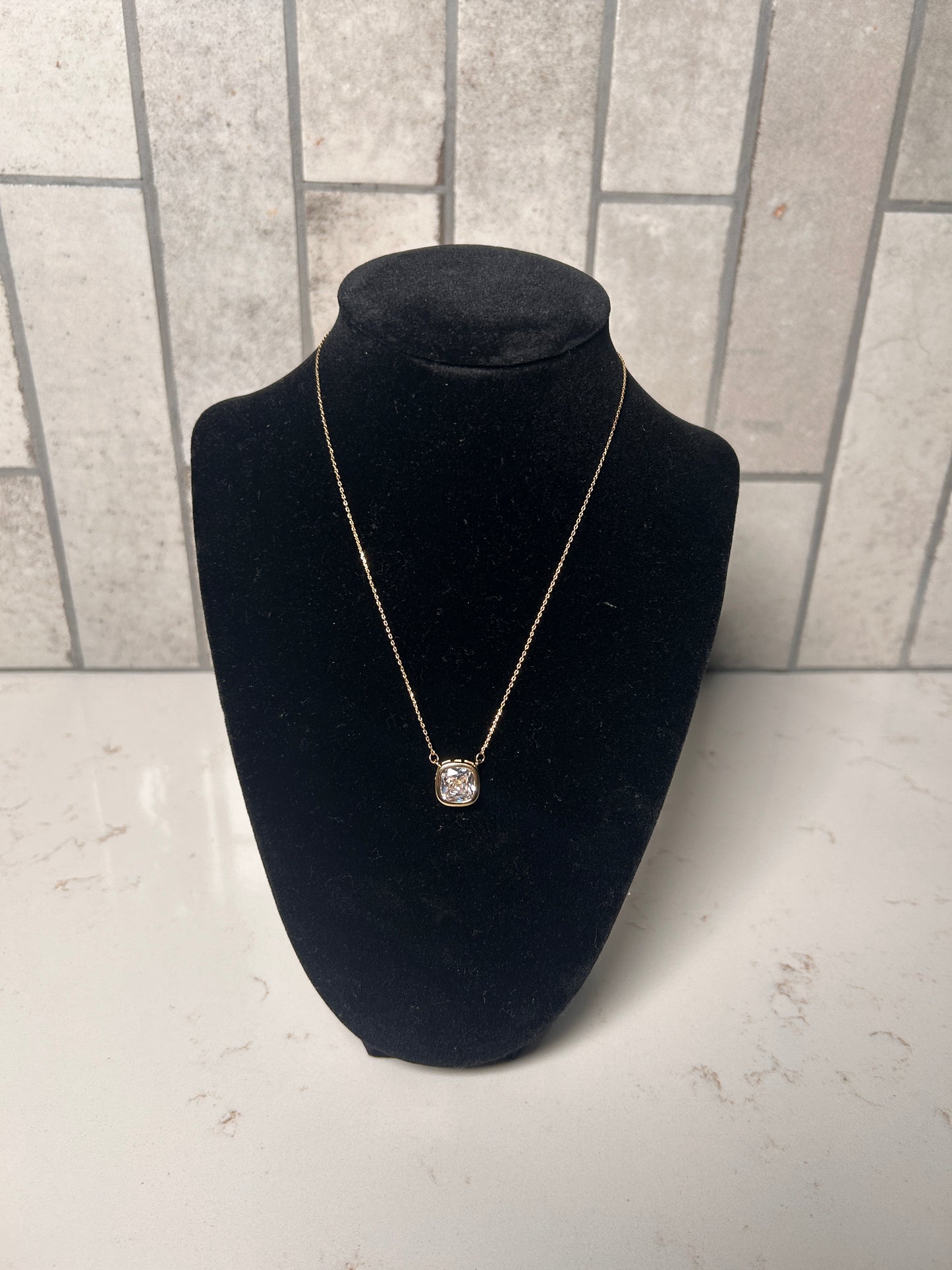 Cushion cut bezel diamond necklace on a delicate gold chain, minimalist women’s jewelry displayed on black bust