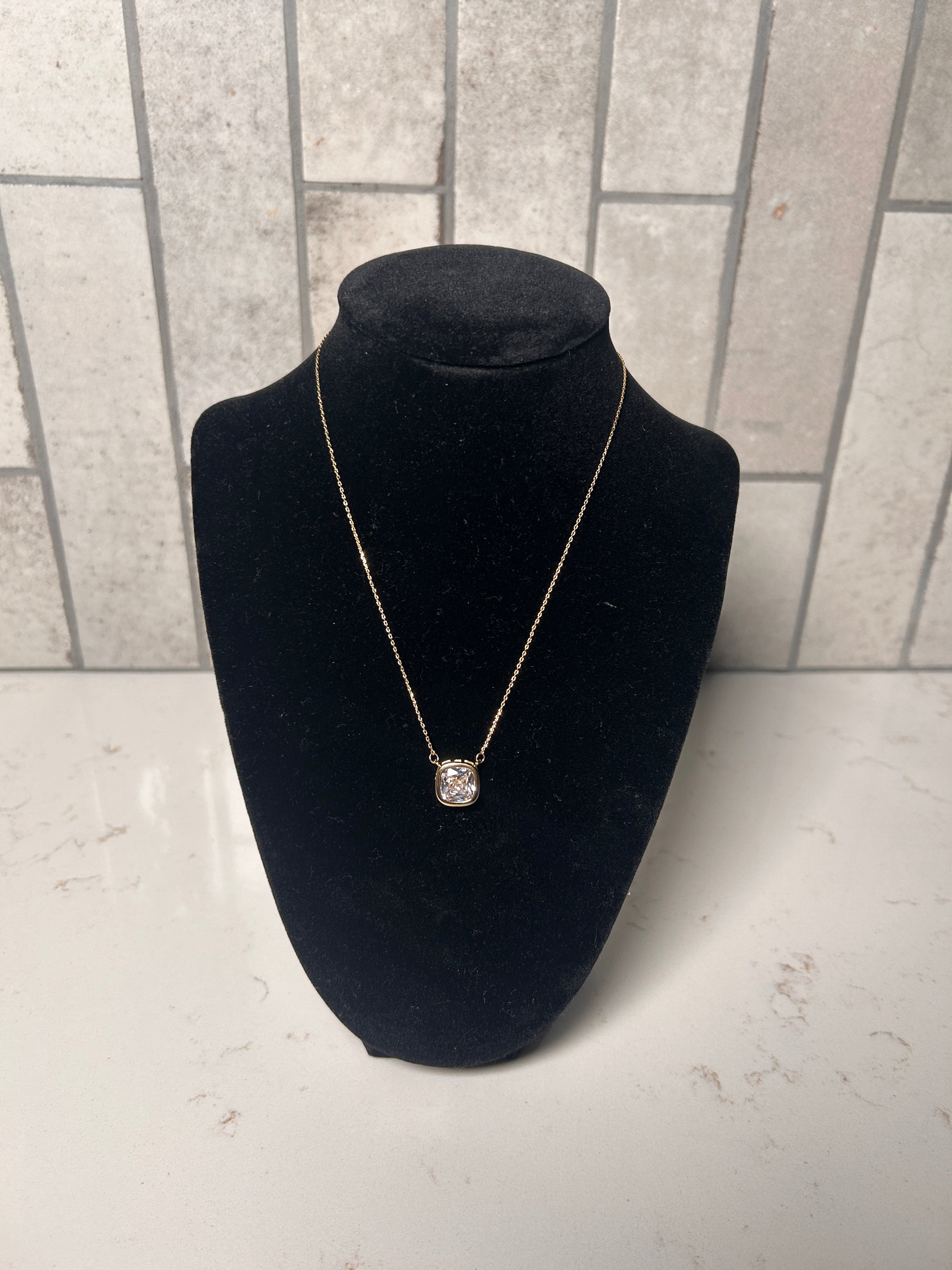 Cushion cut bezel diamond necklace on a delicate gold chain, minimalist women’s jewelry displayed on black bust