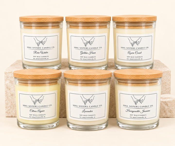 Soul Sisters Candle Co. Everyday Collection featuring six hand-poured soy wax candles in Rain Water, Golden Hour, Azure Coast, Citrus Agave, Lavender, and Honeysuckle Jasmine, displayed in clear glass jars with natural bamboo lids on a cream studio background.