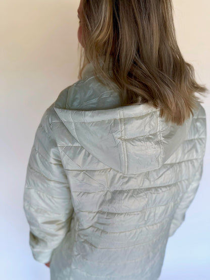 Person wearing a light green quilted jacket against a white background