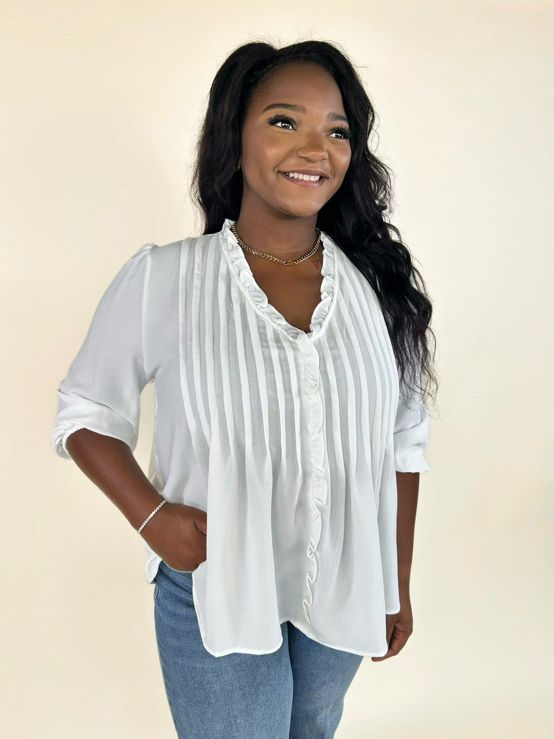 Woman wearing a white pintuck blouse with wide-leg jeans for a casual everyday outfit.