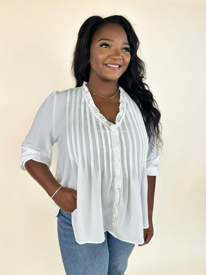 Woman wearing a white pintuck blouse with wide-leg jeans for a casual everyday outfit.