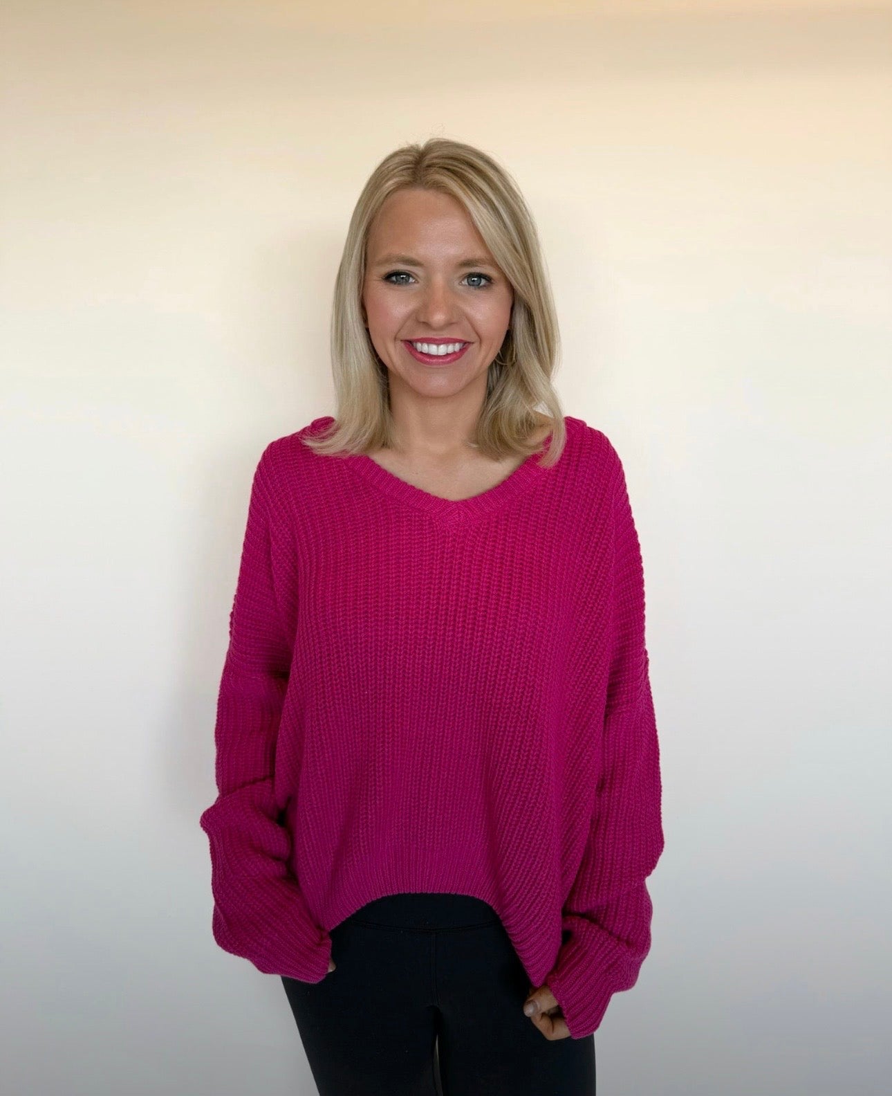 Woman wearing a pink sweater against a plain background