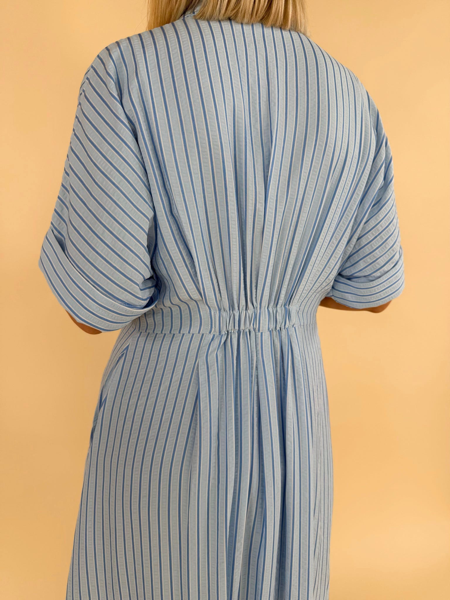 Close up back detail of light blue striped midi dress with elastic waist women’s boutique clothing