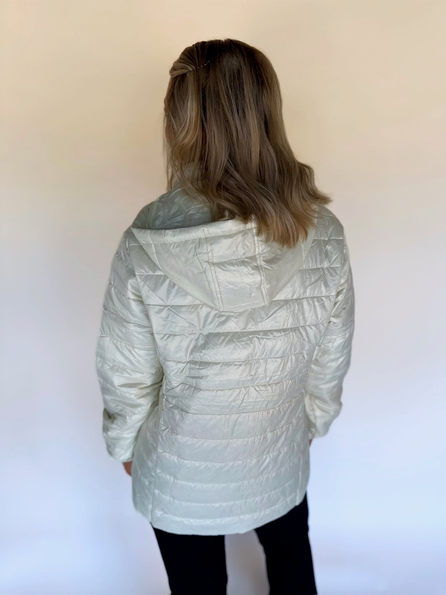 Person wearing an ivory quilted jacket on a white background