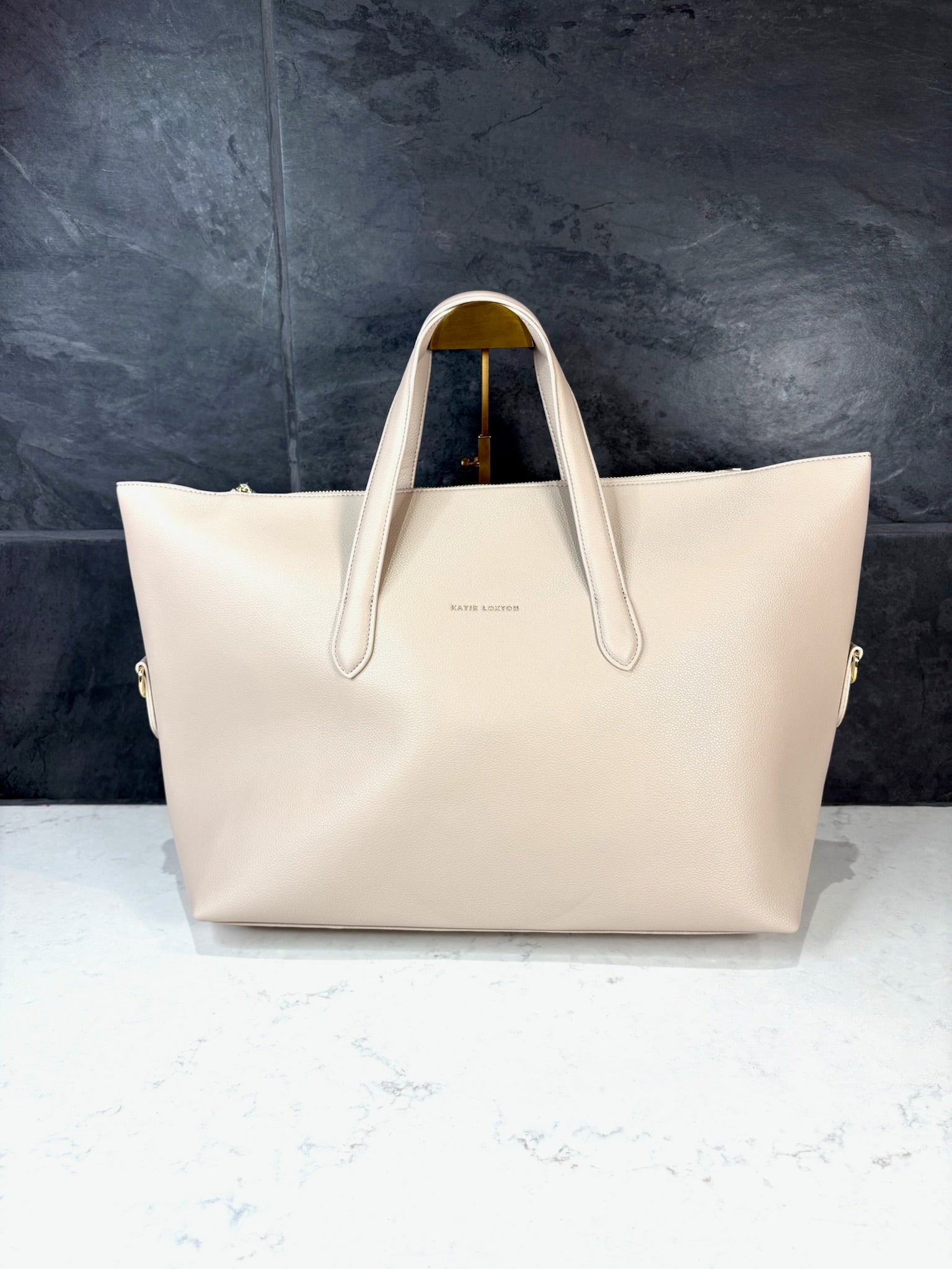 Milan Cabin Bag in Oyster by Katie Loxton, oversized vegan leather travel tote with top handles and gold hardware.
