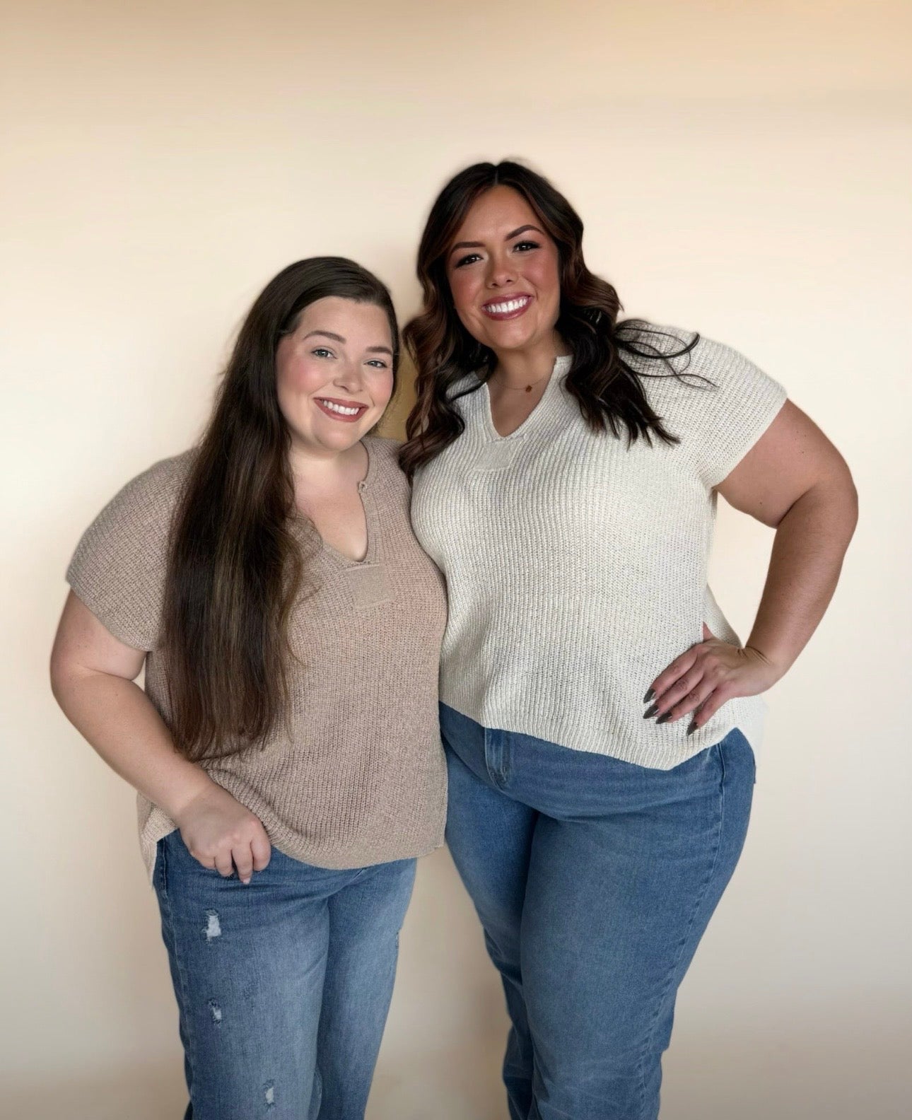 Two women standing together wearing matching outfits with a plain background