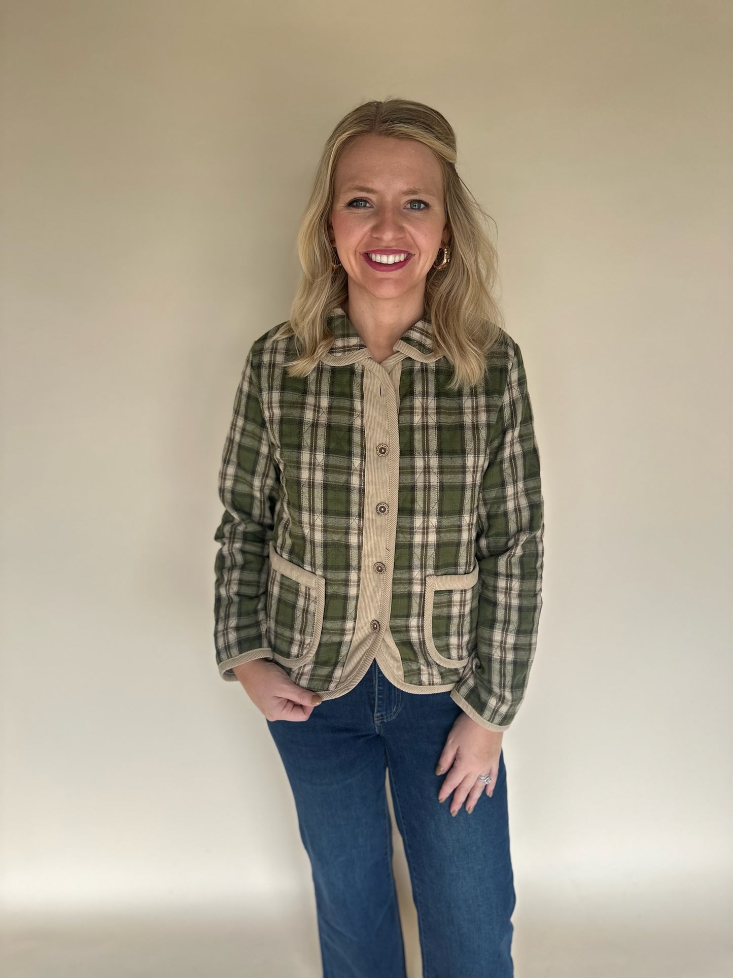 Front view of green and tan plaid button-front jacket with tan corduroy trim and curved pockets, styled with blue jeans.