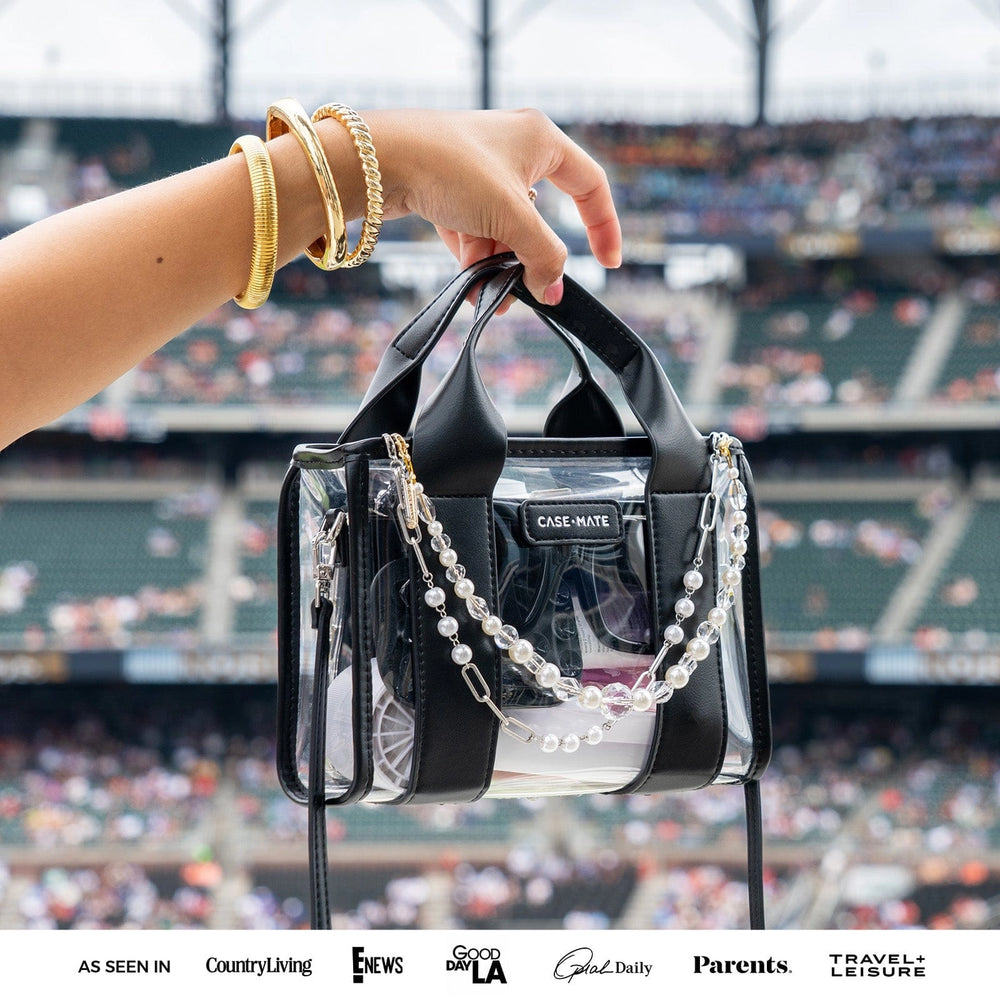 Case-Mate Clear Stadium Bag in Midnight Black held at a sporting event with black handles, clear body and decorative charms shown for styling.