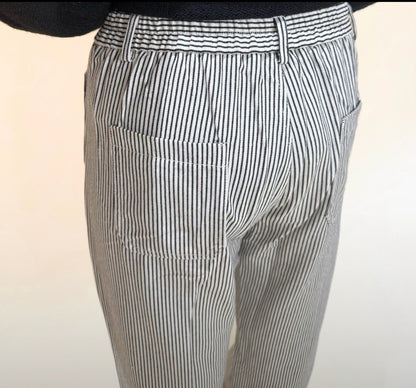 Close-up back view of black and white vertical stripe pants highlighting waistband, belt loops, and back pocket stitching.