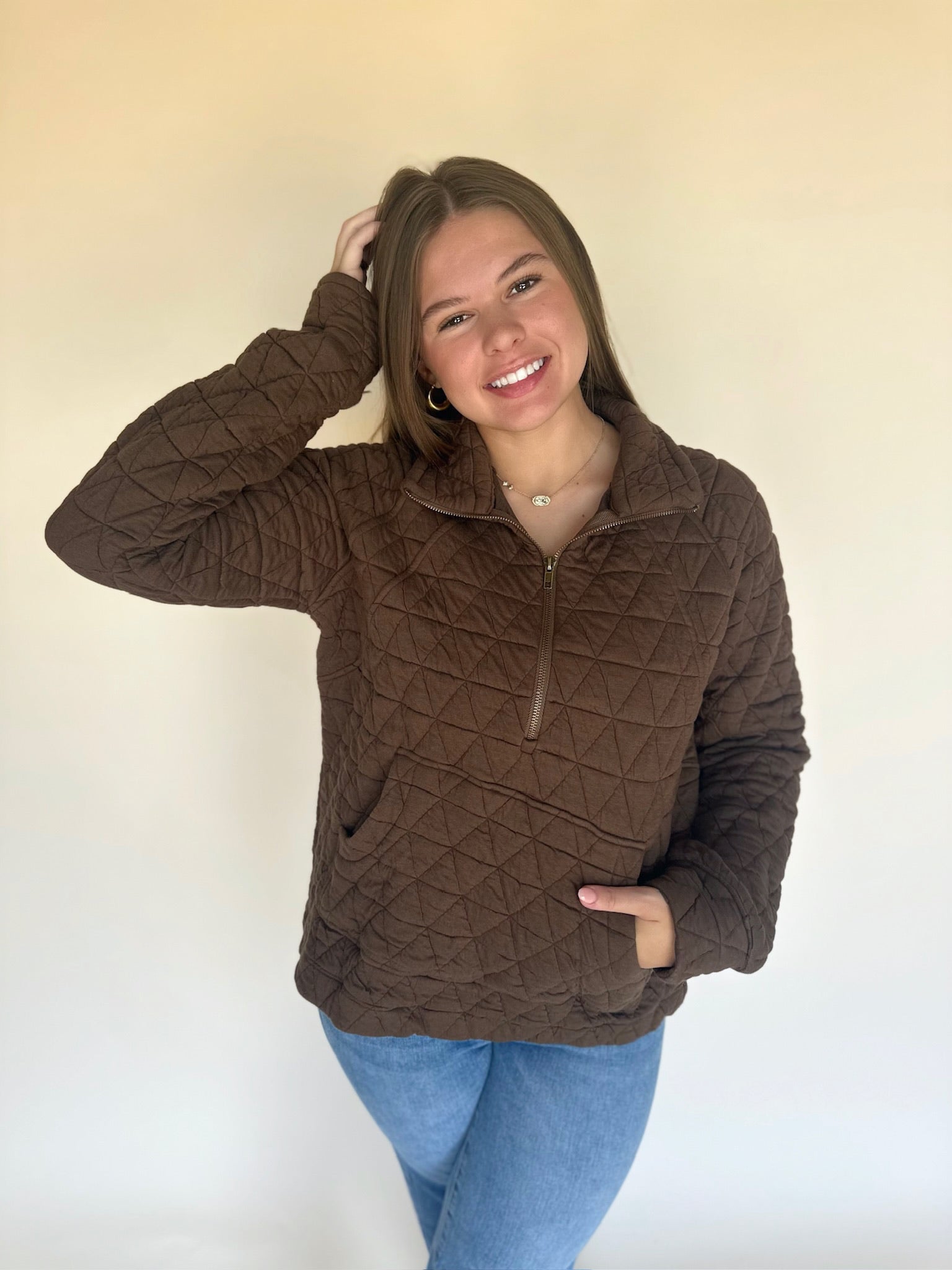 Woman wearing a brown quilted jacket against a plain background