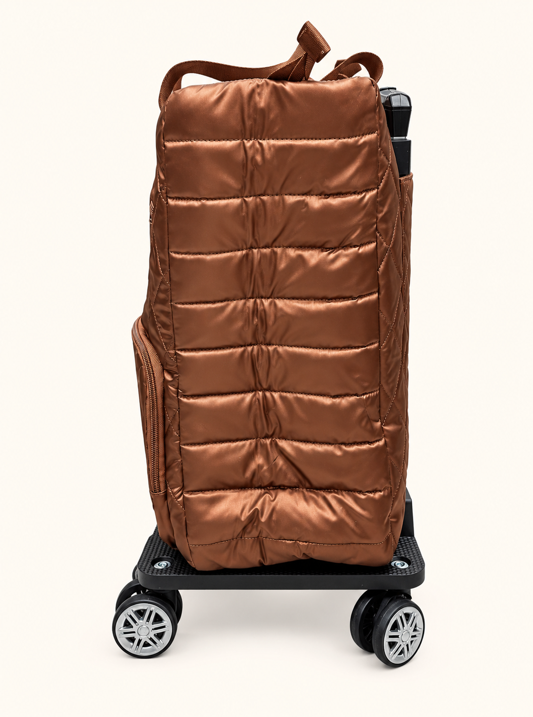 Side view of Simply Southern copper swivel rolling tote showing metallic bronze fabric, horizontal padded quilting, side zipper pocket, and spinner wheels.