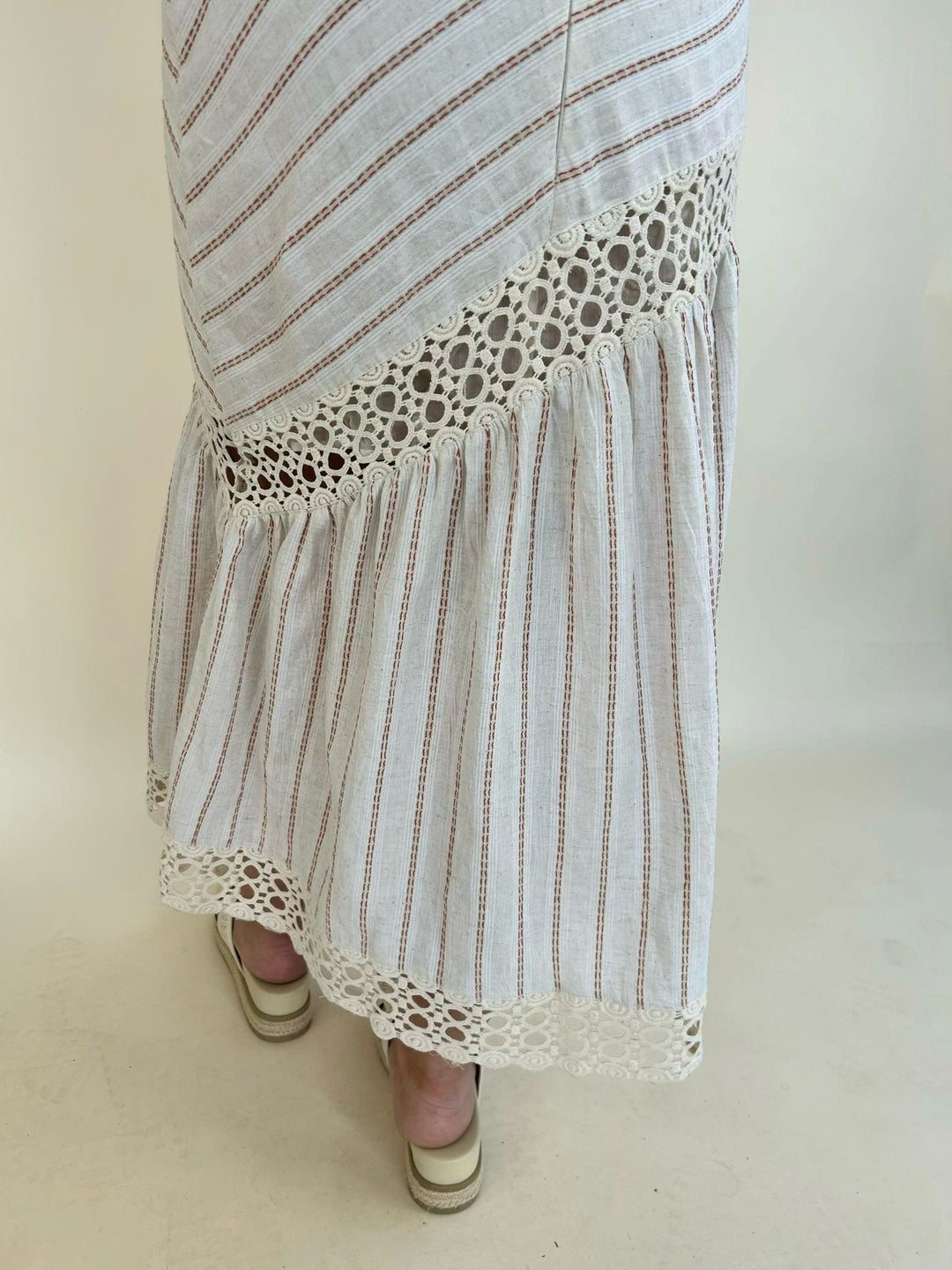 Close-up of the Bella Halter Cutout Tiered Maxi Dress highlighting the tiered skirt, crochet lace trim, and striped textured fabric.