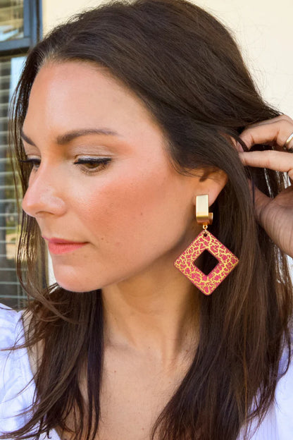 Woman wearing a red and gold earring with a neutral background