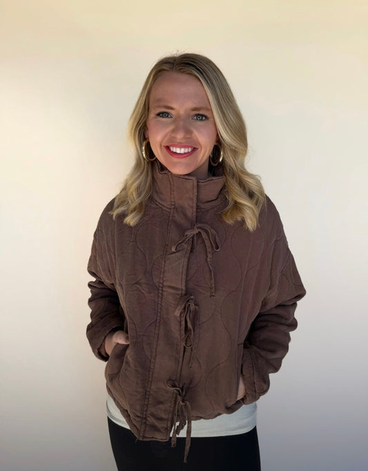 Woman wearing a brown jacket against a plain background