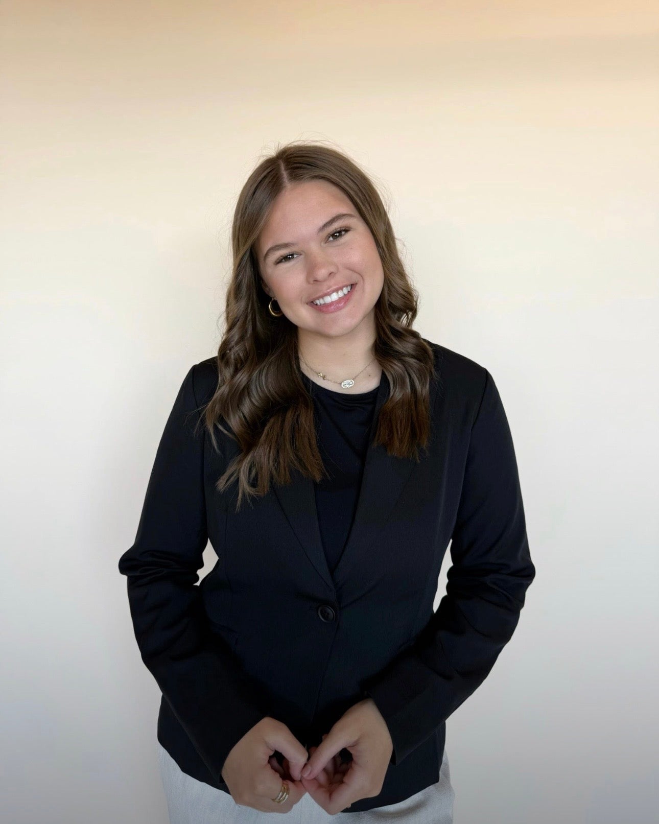 Person wearing a black blazer against a plain background