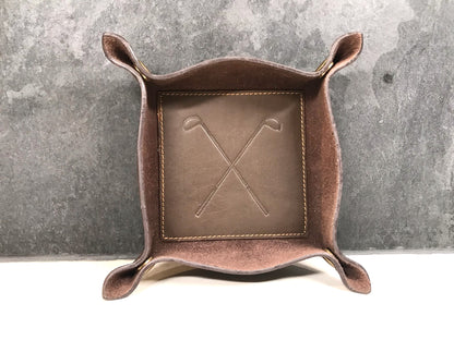 Brown leather catch-all tray with embossed design on a gray background