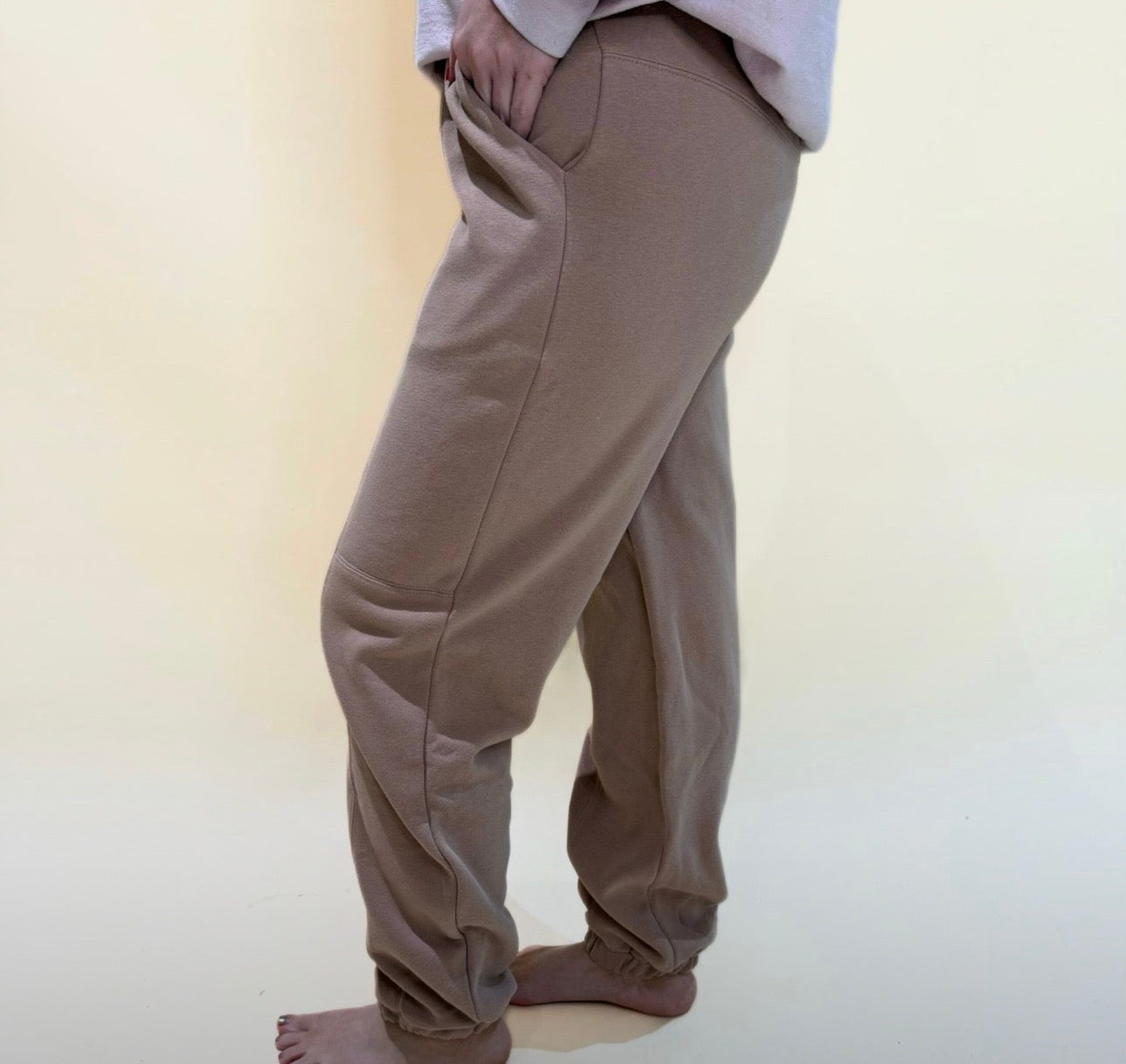 Side view of taupe jogger pants featuring pockets, soft stretch fabric, and a loose comfortable silhouette.
