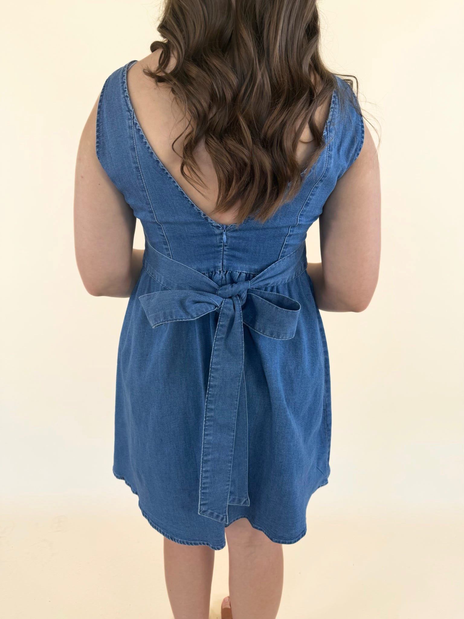 Back view of baby blue denim dress featuring adjustable tie-back waist and soft denim fabric