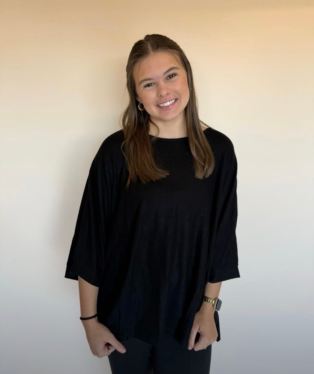 Person wearing a black top against a plain background