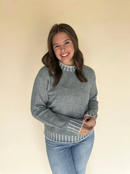 Woman wearing light blue sweater with white trim on a beige background