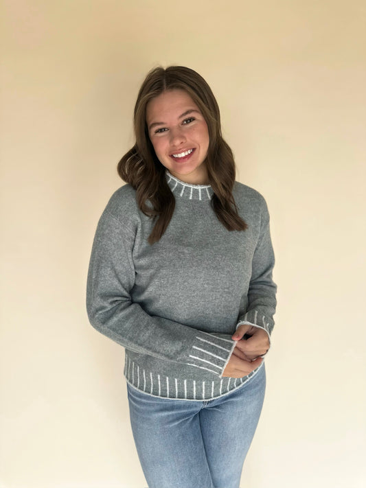 Woman wearing light blue sweater with white trim on a beige background