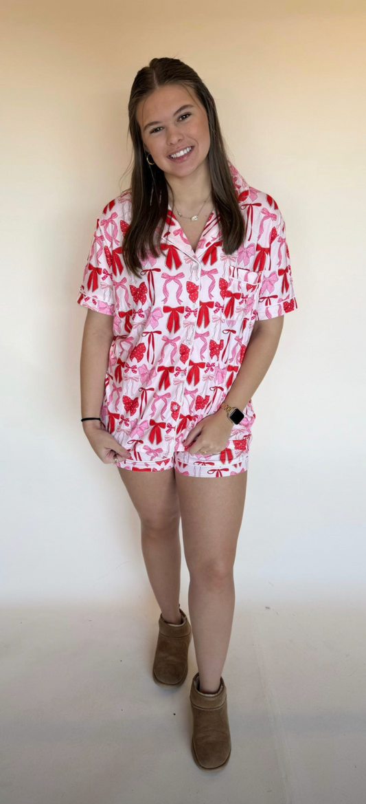 Woman wearing a red and white patterned lounge set against a plain background