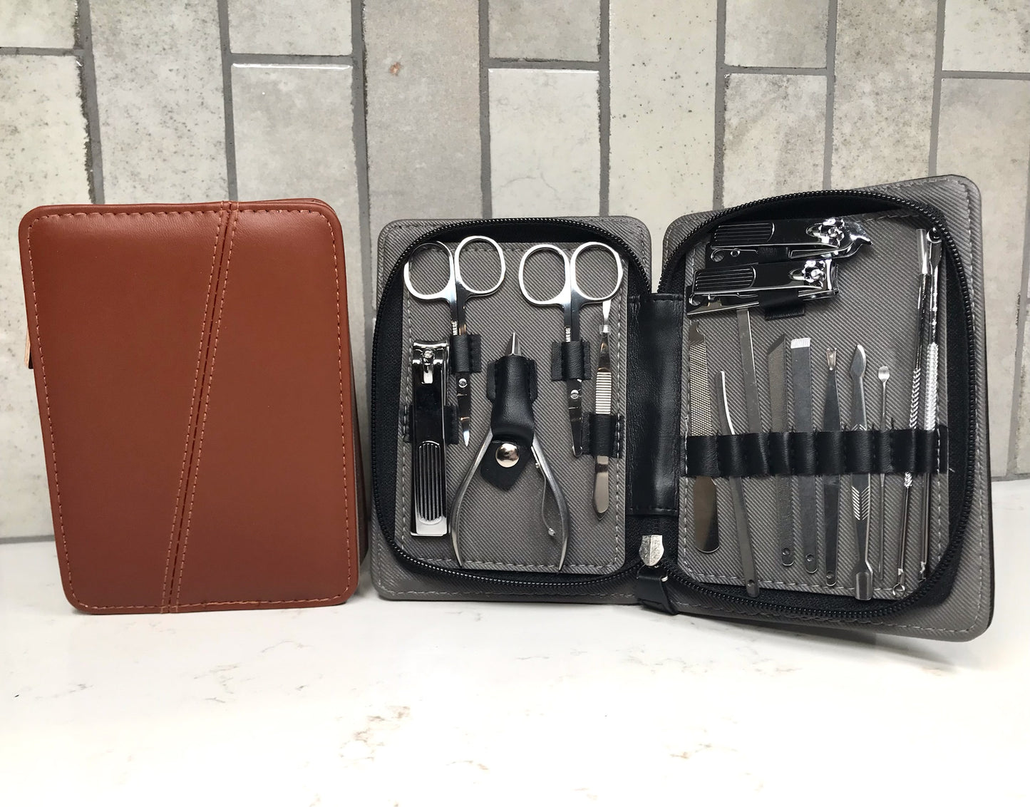 Manicure set with tools in an open case on a white surface with a tiled wall background