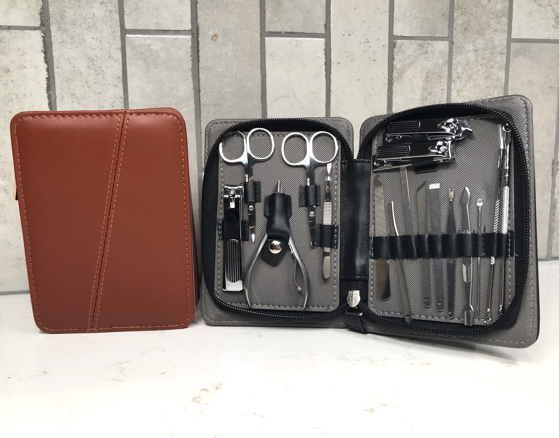 Manicure set with tools in an open case on a white surface with a tiled wall background