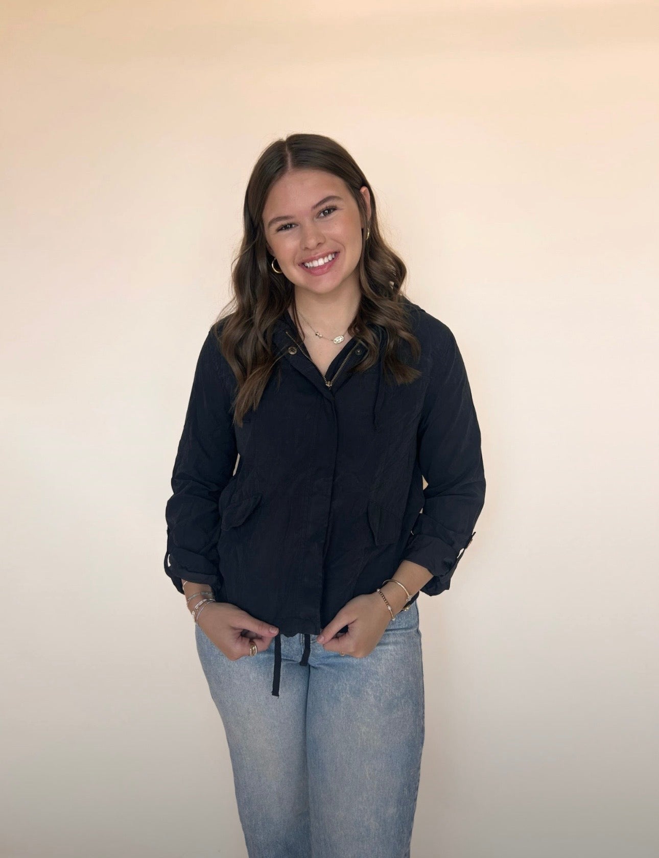 Woman wearing a black shirt and light blue jeans against a plain background