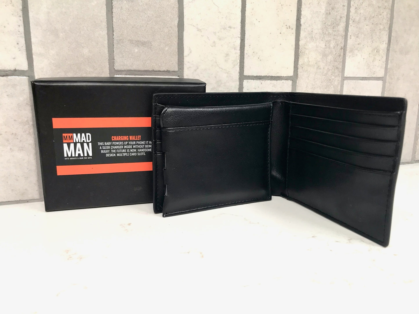 Black leather wallet with open design and 'MAD MAN' branding on a tiled wall background