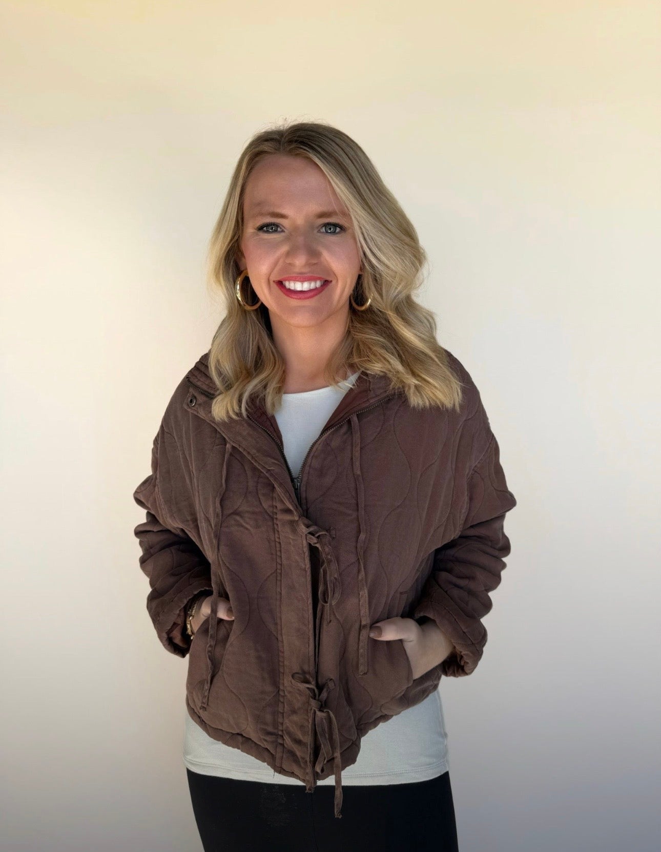 Woman wearing a brown jacket against a plain background