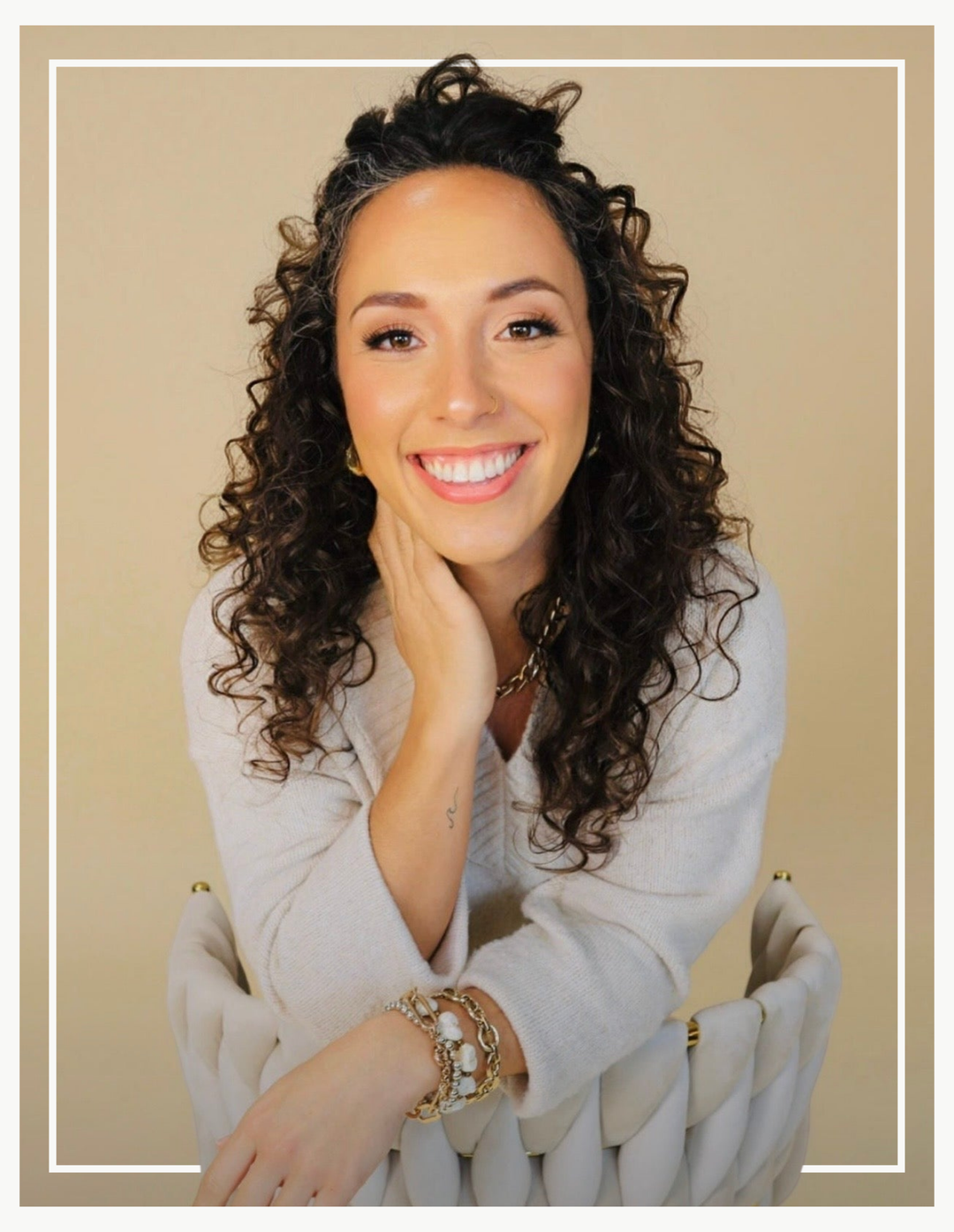 Woman with curly hair smiling against a beige background