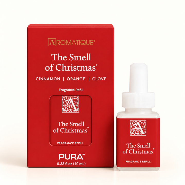 Aromatique The Smell of Christmas Pura 10 mL home fragrance diffuser refill bottle displayed beside festive red packaging, featuring cinnamon, orange, and clove scent notes on a cream background.