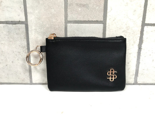 Black pouch with gold zipper and key ring on a tiled background