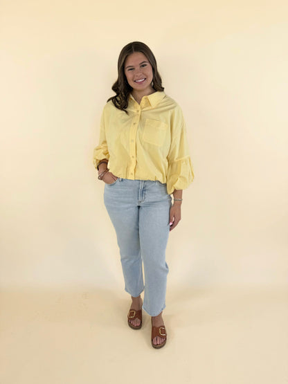 Woman wearing banana cream yellow bubble sleeve button-down top with light wash jeans and brown sandals