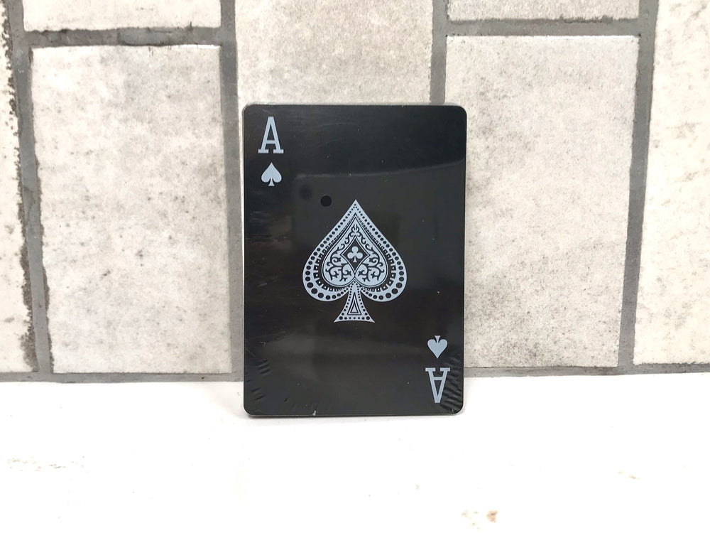 Ace of Spades from the Mad Man Waterproof Black Edition Playing Card deck featuring a black background and silver artwork