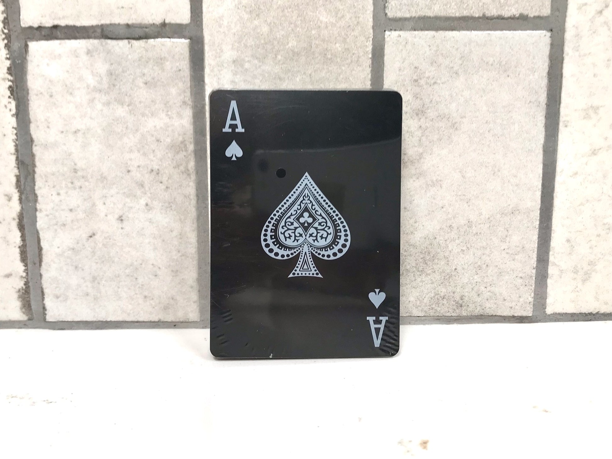 Black playing card with white spade symbol on a tiled background