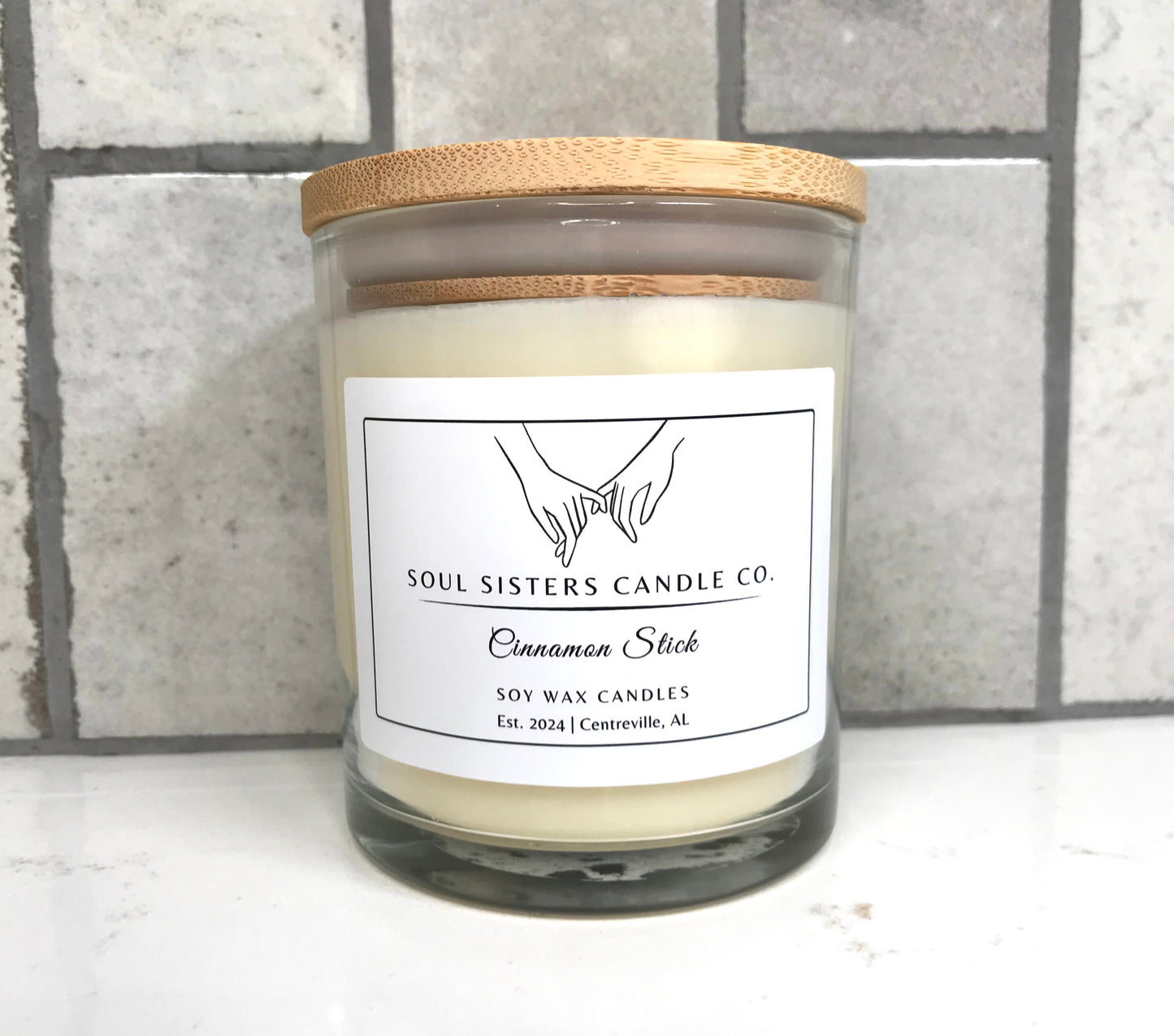 Soul Sisters Candle Co. candle with wooden lid on a tiled wall background