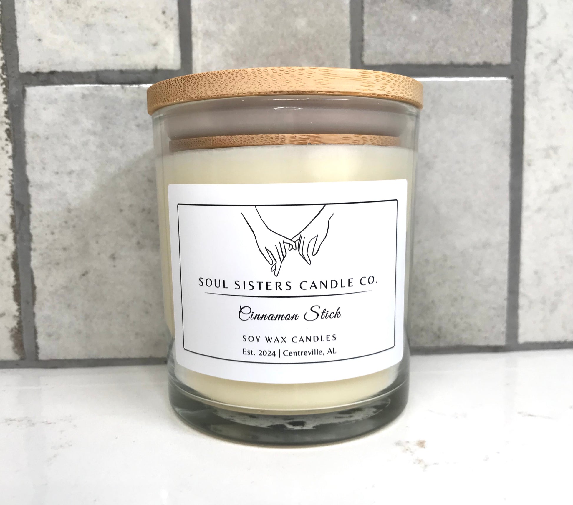 Soul Sisters Candle Co. candle with wooden lid on a tiled wall background