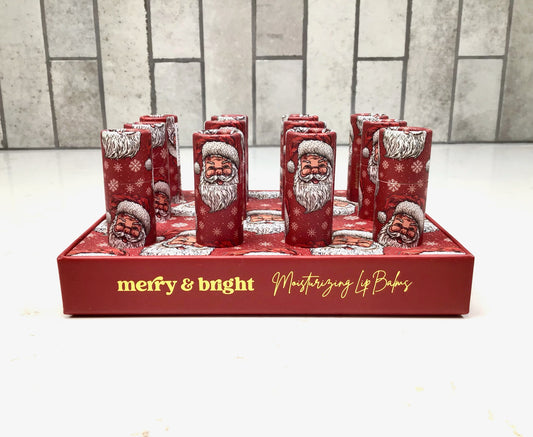 Set of red lip balm containers with Santa Claus design on a red tray with 'merry & bright' text.
