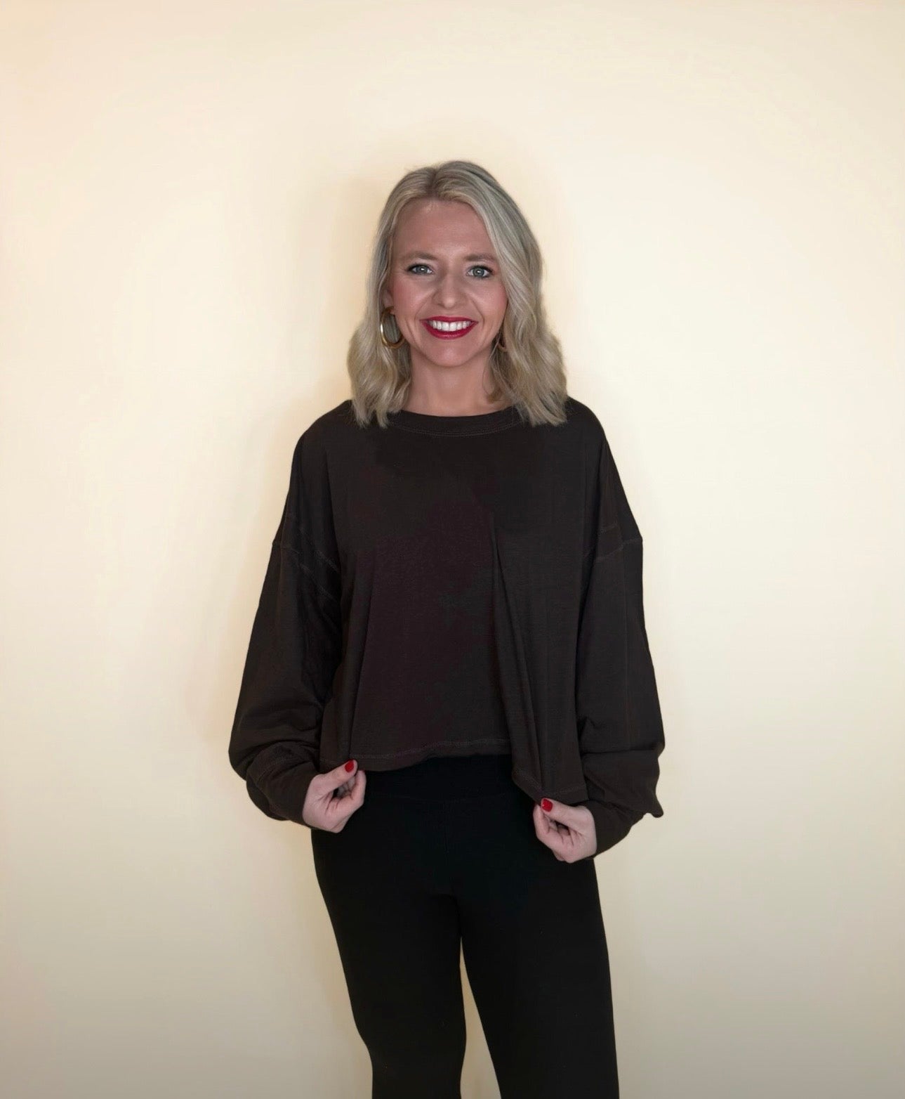 Woman wearing a dark brown oversized long sleeve top with black pants, loose lightweight knit for cozy casual style.