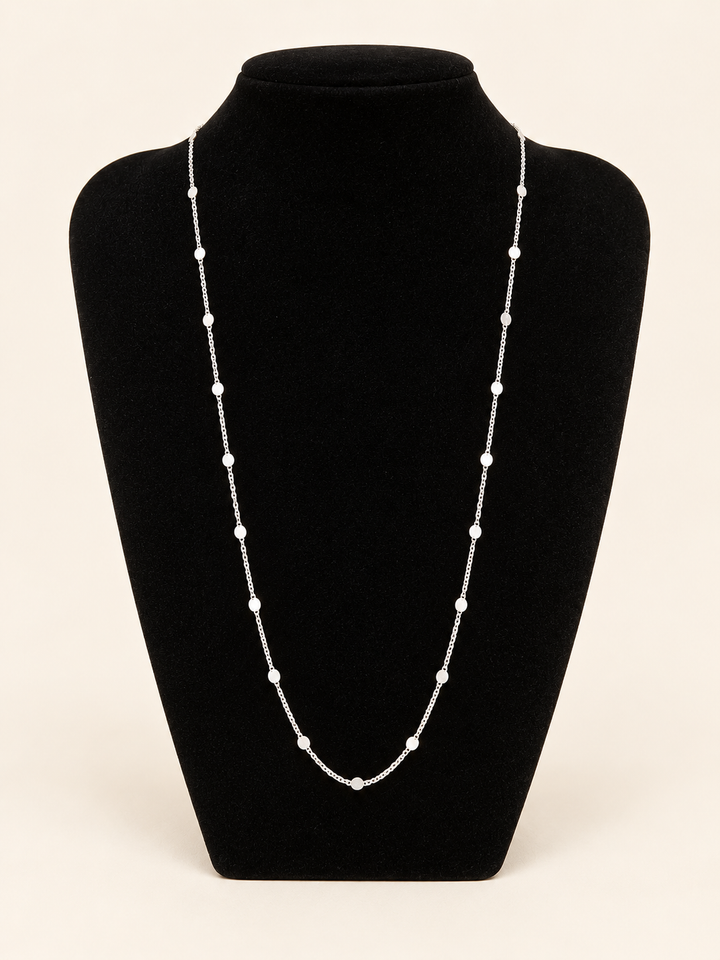 Long silver flat disc station chain necklace displayed on a black velvet jewelry bust with evenly spaced round accents.