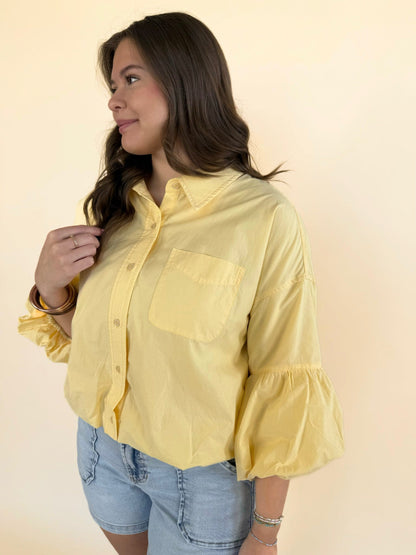 Close-up of yellow cotton bubble sleeve blouse with collar, chest pocket, and balloon sleeves
