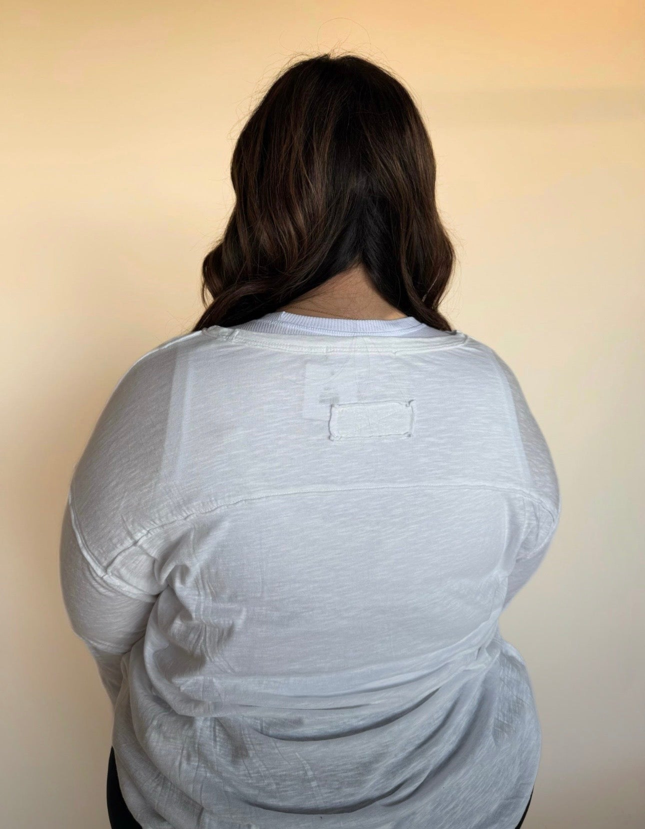 Person wearing a white t-shirt against a beige background
