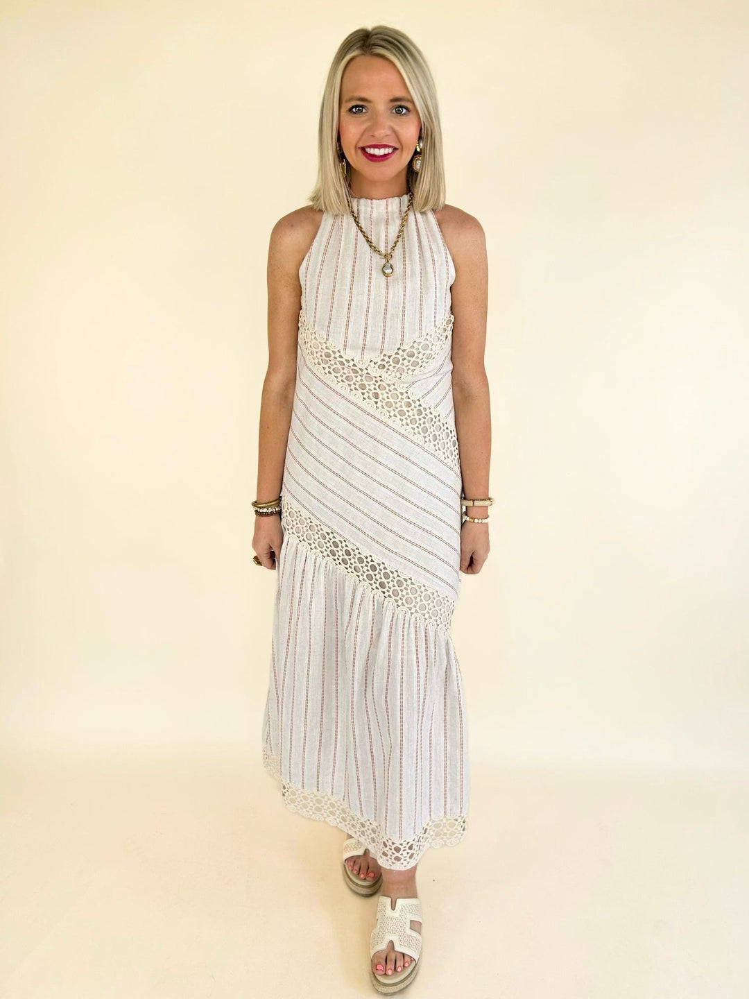 Woman wearing the Bella Halter Cutout Tiered Maxi Dress featuring a halter neckline, crochet lace accents, subtle cutout detail, and a flowy tiered skirt.