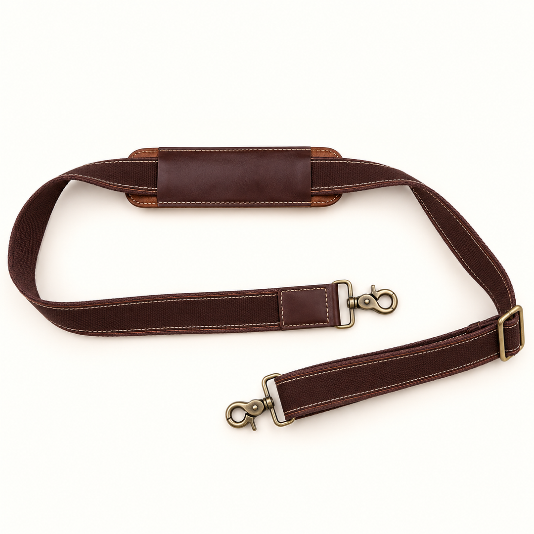Adjustable detachable brown shoulder strap for the Dusty Duffel leather travel bag, featuring a padded shoulder section, contrast stitching, and antique brass swivel clips.