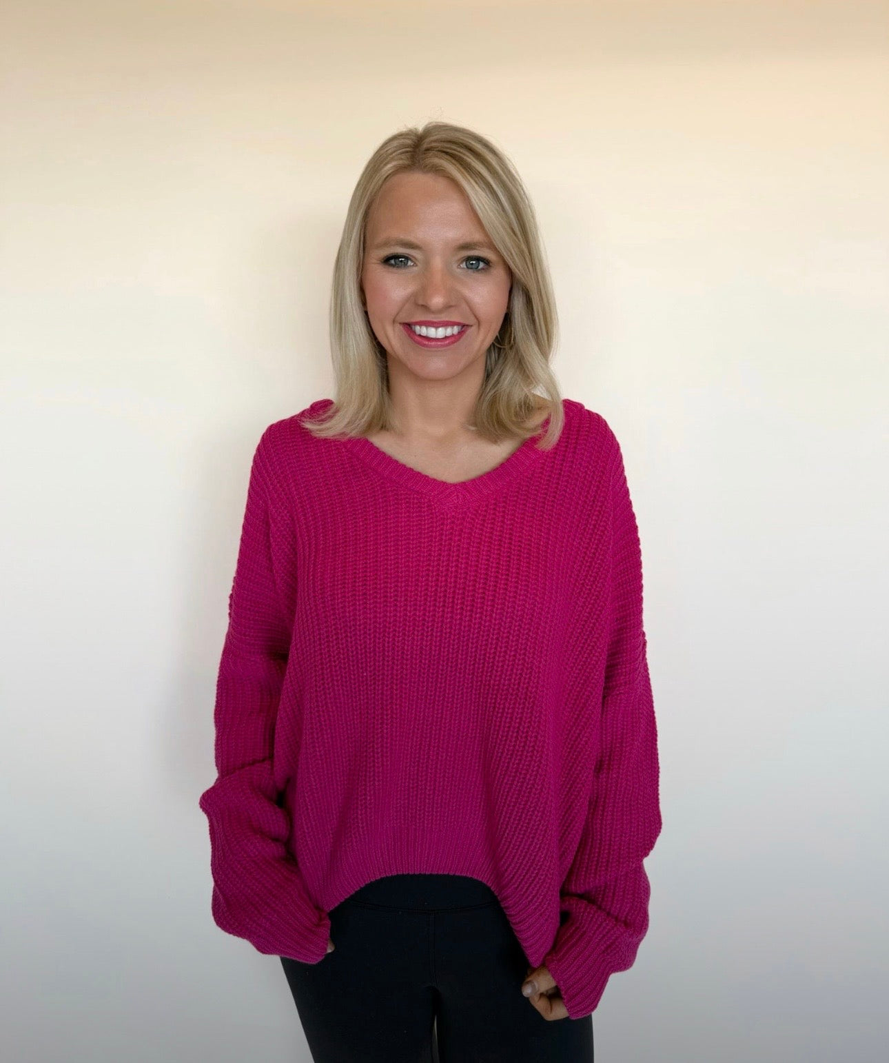 Woman wearing a pink sweater against a plain background