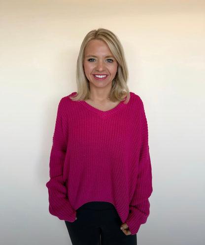 Woman wearing a pink sweater against a plain background